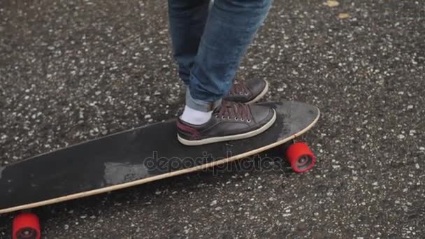 Mand ridning på en longboard skate på en vej gennem en skov – Stock-video