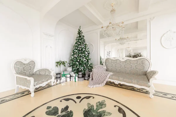 Julafton. klassiska lägenheter med en vit öppen spis, dekorerat träd, ljus soffa, stora fönster — Stockfoto