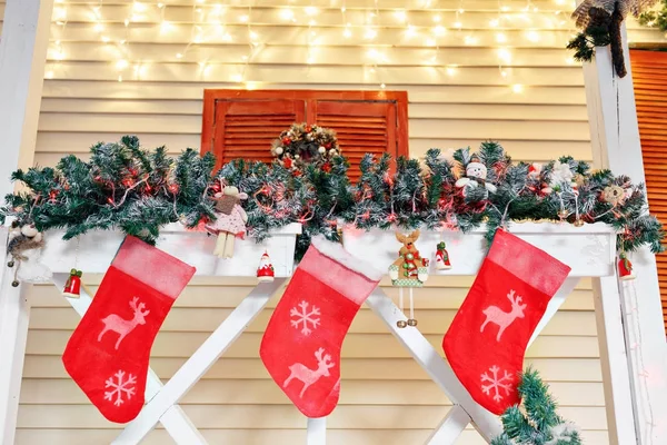Χριστουγεννιάτικη κάλτσα και διακόσμηση σε ξύλο. στη βεράντα του φωτεινό με γιρλάντες — Φωτογραφία Αρχείου