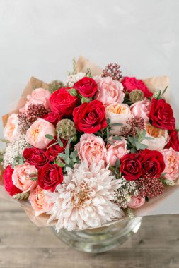 Cam vazoda karışık çiçekli buket. Ahşap Komiteler Masası üzerinde standı