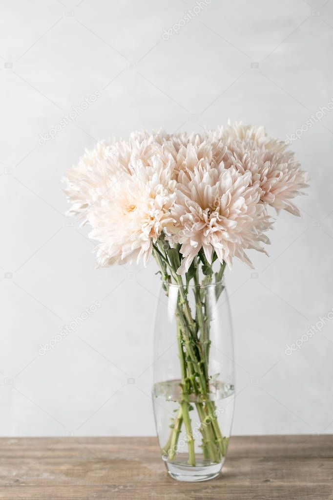 Vase with white chrysanthemum on a table of wooden planks