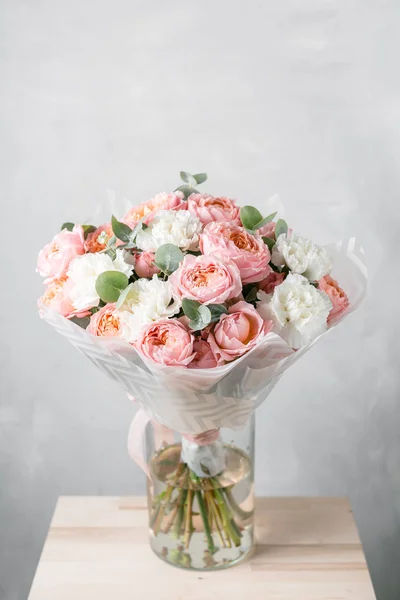 Bouquet de fleurs mélangées dans un vase en verre. Stand sur le bureau de planches en bois — Photo