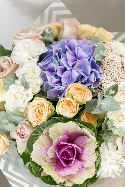 beautiful bouquet of mixed flowers into a vase on wooden table
