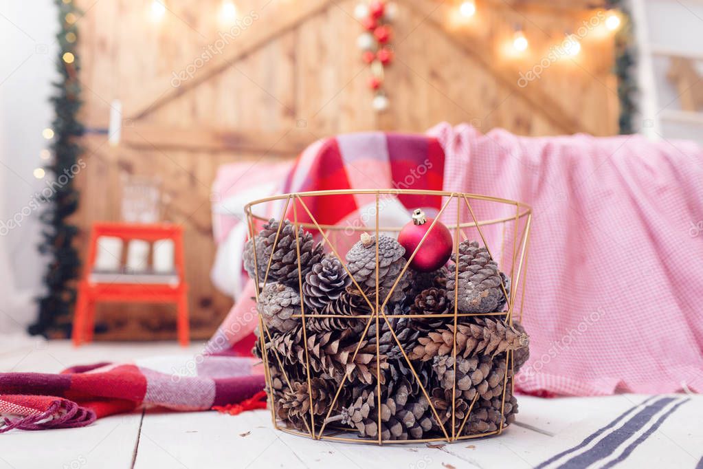 Christmas decorations in basket and pine cones on floor close up.