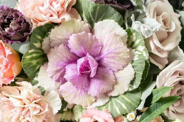 beautiful bouquet of mixed flowers into a vase on wooden table. copy space