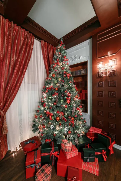 Noche de Navidad. apartamentos clásicos con chimenea blanca, árbol decorado, sofá, grandes ventanales y lámpara de araña . —  Fotos de Stock