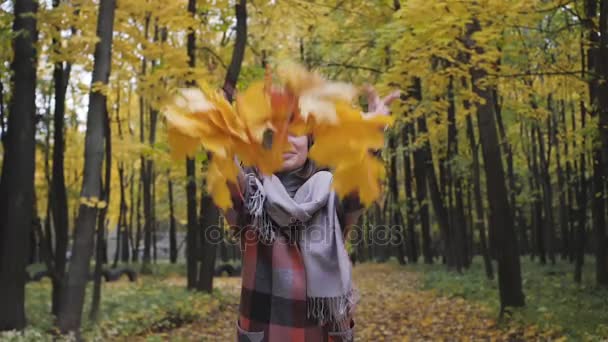 Ρίχνουν τα κορυφαία κίτρινα φύλλα. Φθινόπωρο κοπέλα περπάτημα στο πάρκο της πόλης. Πορτρέτο της ευτυχής όμορφη και όμορφη νεαρή γυναίκα στο δάσος σε χρώματα πτώση. — Αρχείο Βίντεο