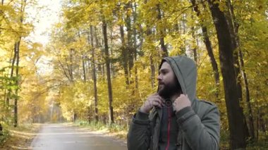 Giysi hood. Yakışıklı delikanlı bir sonbahar ormanda yürüyüş bir ceket giymiş. Parkta niteliğine portre. Ormanda yolda hareket