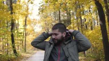 Giysi hood. Yakışıklı delikanlı bir sonbahar ormanda yürüyüş bir ceket giymiş. Parkta niteliğine portre. Ormanda yolda hareket