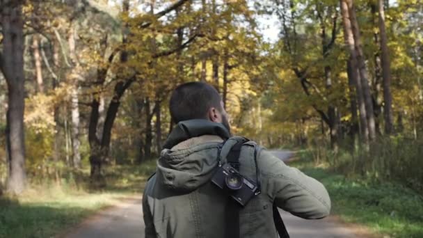 Yakışıklı delikanlı bir sonbahar ormanda yürüyüş bir ceket giymiş. Parkta niteliğine portre. Ormanda yolda hareket — Stok video