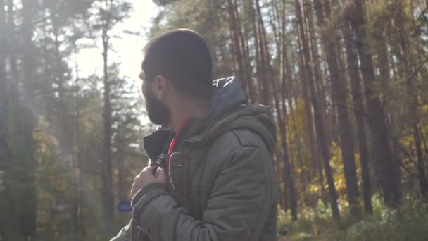 Giovane bell'uomo vestito con una giacca che cammina in una foresta autunnale. Ritratto sulla natura del parco. Spostarsi sulla strada del bosco — Video Stock