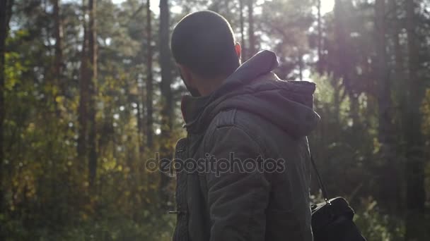 Ung vacker man klädd i en jacka som går i en höst skog. Porträtt på arten av parken. Flytta på skogen vägen — Stockvideo