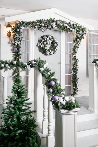 Ház bejáratának díszített ünnepekre. Karácsonyi dekoráció. Garland fenyő fa ágai és a fények a korlát — Stock Fotó