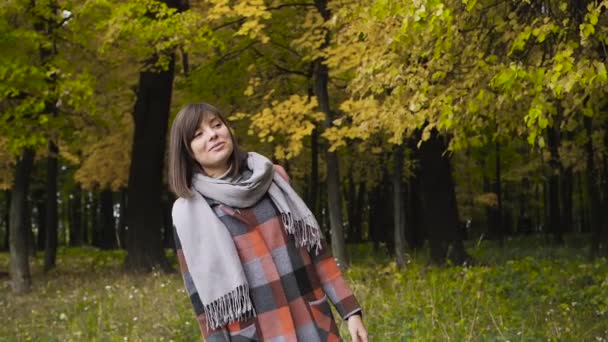 Hösten flicka vandrar i stadsparken. Porträtt av glad trevlig och vacker ung kvinna i skog i höstfärger. — Stockvideo