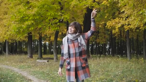 Hösten flicka vandrar i stadsparken. Porträtt av glad trevlig och vacker ung kvinna i skog i höstfärger. — Stockvideo