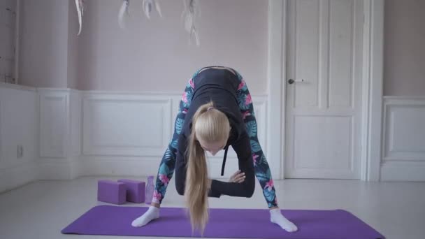 Домашний фитнес. Молодая женщина разогревается перед тренировкой, делая упражнения, чтобы растянуть мышцы и суставы — стоковое видео