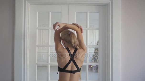 Home fitness. Young woman warming up before training doing exercises to stretch her muscles and joints — Stock Video