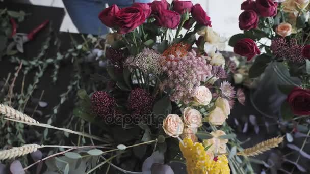 Master class de fleuriste féminine au travail avec un bouquet de fleurs. Fille faisant bouquet de diverses fleurs d'automne. Femme d'affaires fleuriste à la boutique de fleurs — Video