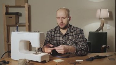 İyi görünümlü genç bir terzi çalışan ve bir dikiş makinesi bir tekstil Studio'yu kullanarak adam. papyon yapar