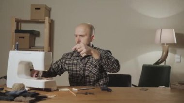 genç adam makinede iplik makarası ayarlar. Bir terzi çalışan ve bir dikiş makinesi bir tekstil Studio'yu kullanarak. papyon yapar