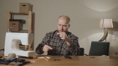 Yakın çekim yünden bir kelebek kravat şeklini oluşturur. Bir terzi çalışan ve bir dikiş makinesi bir tekstil Studio'yu kullanarak iyi görünümlü genç adam.