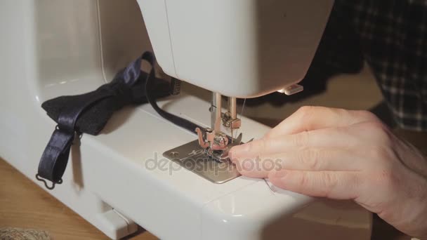 Gut aussehender junger Mann, der als Schneider arbeitet und in einem Textilatelier eine Nähmaschine bedient. macht Fliege — Stockvideo