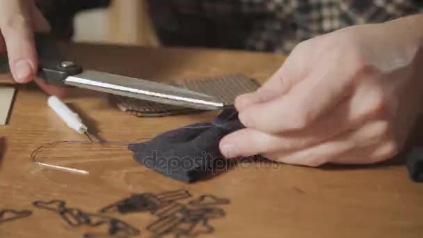 Tagliare il filo. Il primo piano crea la forma di una cravatta a farfalla in lana. Bel ragazzo che lavora come sarto e utilizza una macchina da cucire in uno studio tessile . — Video Stock