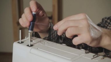 genç adam makinede iplik makarası ayarlar. Bir terzi çalışan ve bir dikiş makinesi bir tekstil Studio'yu kullanarak. papyon yapar