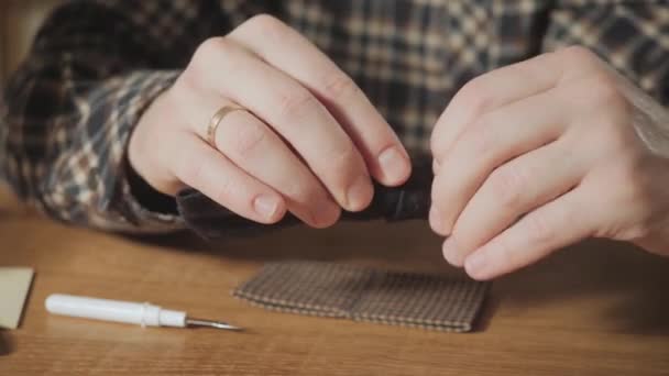 Close-up crea la forma de una corbata de mariposa hecha de lana. Joven apuesto trabajando como sastre y usando una máquina de coser en un estudio textil . — Vídeo de stock