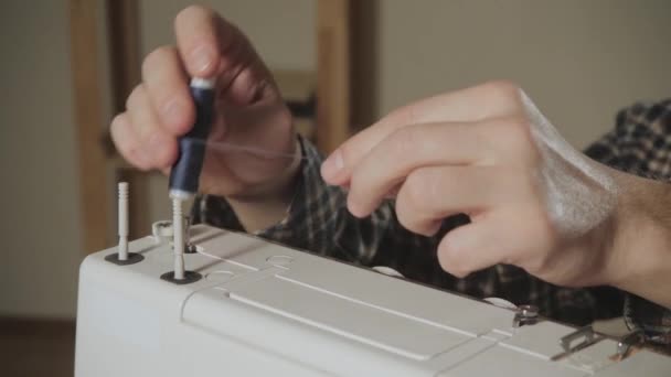 Jongeman wordt de spoel van draad ingesteld op de machine. Werken als een kleermaker en een naaimachine gebruiken in een textiel-studio. maakt strikjes — Stockvideo