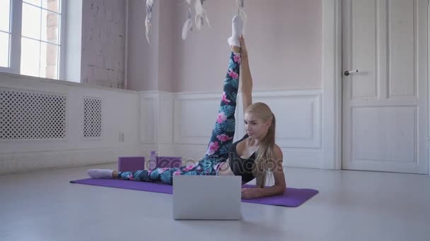 Heimfitness. junge Frau beim Training. Muskeln und Gelenke dehnen. Videos im Internet auf dem Laptop ansehen — Stockvideo