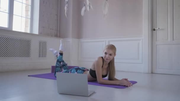 Domácí fitness. Mladá žena trénink dělá. Protažení svalů a kloubů. Sledování videa na internetu na notebooku — Stock video