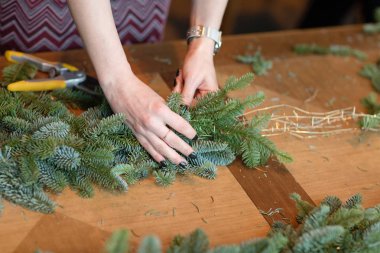 İş yerinde çiçekçi: kadın el Noel süslemeleri çelenk köknar yapım. Mutlu yeni yıl akşam yemeği bayram