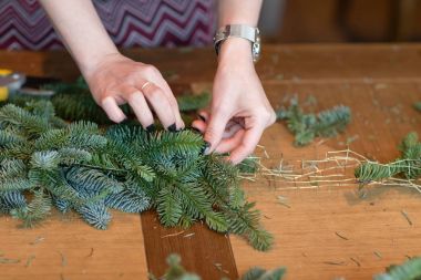 İş yerinde çiçekçi: kadın el Noel süslemeleri çelenk köknar yapım. Mutlu yeni yıl akşam yemeği bayram