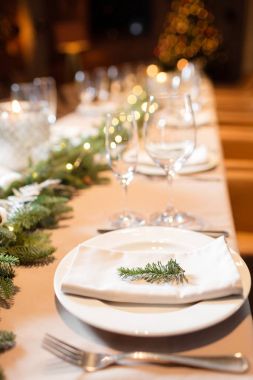 Noel yemeği bayram etsin. Şampanya bardağı ve arka planda Noel ağacı ile dekore edilmiş bir yemek masası