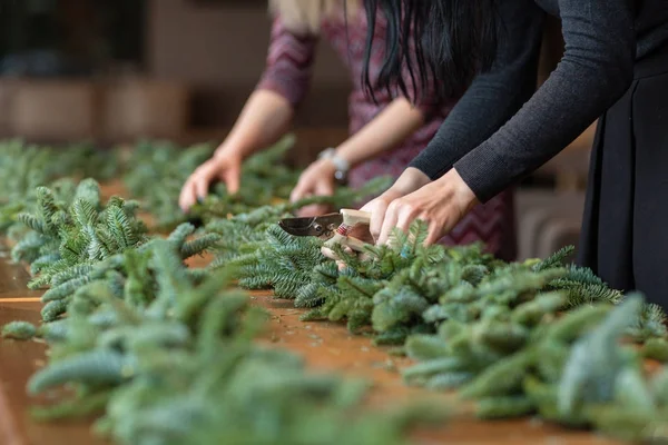 Florist at work: woman hands making christmas decorations garland of fir. Happy new year dinner feast