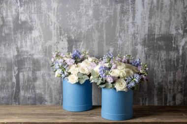 mavi bir şapka kutusunda iki çiçek buketi. ahşap bir masa üzerinde duran. Arka plan eski gri duvar sanat. kopya alanı.