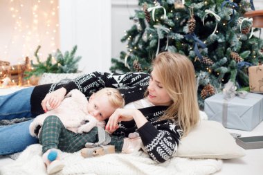 Noel ve yeni yıl kutlama. Mutlu anne ve kızı yakınındaki xmas hediye ile Noel ağacı kucaklayan. Arka plan üzerinde beyaz şömine