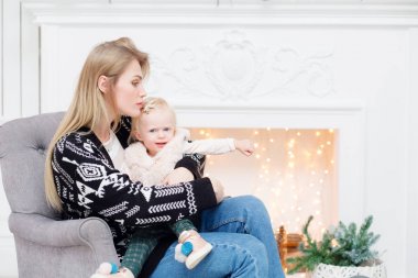 Noel ve yeni yıl kutlama. Mutlu anne ve kızı kucaklayan. Arka plan üzerinde beyaz şömine