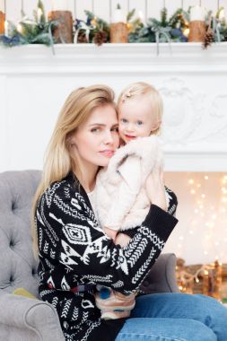 Noel ve yeni yıl kutlama. Mutlu anne ve kızı kucaklayan. Arka plan üzerinde beyaz şömine