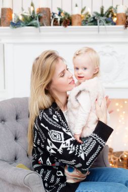 Noel ve yeni yıl kutlama. Mutlu anne ve kızı kucaklayan. Arka plan üzerinde beyaz şömine