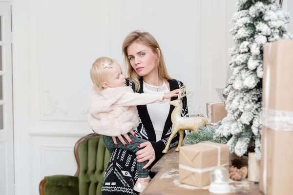 Vánoční a silvestrovské oslavy. Šťastný matka a dcera objímat na vánoční stromeček s vánočními dárky. Starý starožitný příborník — Stock fotografie
