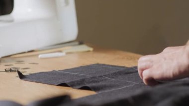 Kesme karanlık yün kumaş. çizgi deseni. Bir terzi çalışma ve atölyede bir dikiş makinesi kullanarak genç adam.
