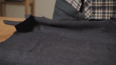 Terzi yün kesim masası üzerinde ortaya konuyor. Bir terzi çalışma ve atölyede bir dikiş makinesi kullanarak genç adam.