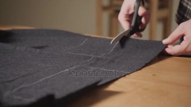 Kesme karanlık yün kumaş. çizgi deseni. Bir terzi çalışma ve atölyede bir dikiş makinesi kullanarak genç adam.