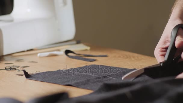 Corte de tela de lana oscura. el patrón de línea. Joven trabajando como sastre y utilizando una máquina de coser en el taller . — Vídeo de stock