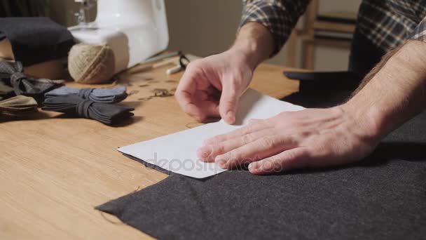 Schneiden von Wollstoffen. das Linienmuster. Fliege aus Wollstoff. junger Mann arbeitet als Schneider und bedient eine Nähmaschine in einem Textilatelier. — Stockvideo