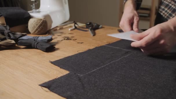 절단 모직 직물입니다. 선 패턴입니다. 모직 직물의 나비 넥타이입니다. 젊은이 재단사로 일 고 섬유 스튜디오에서 재 봉 기계를 사용 하 여. — 비디오