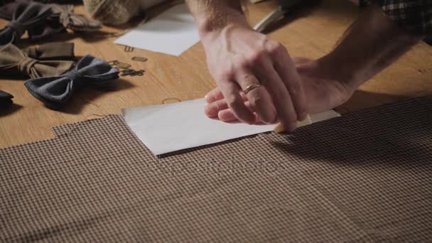 Snijden wollen stof. het lijnpatroon. Strikjes van wollen weefsel. Jonge man werken als een kleermaker en een naaimachine gebruiken in een textiel-studio. — Stockvideo