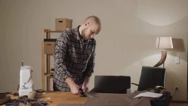 절단 갈색 격자 무늬 모직 직물입니다. 선 패턴입니다. 젊은이 재단사로 일 하 고 워크숍에 봉 제 기계를 사용 하 여. — 비디오